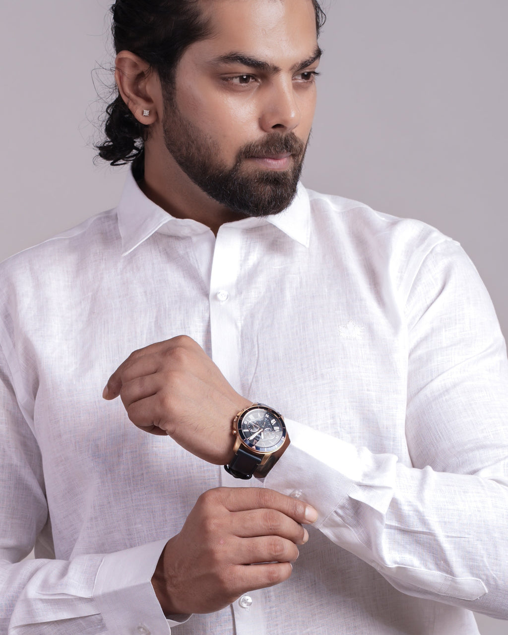 Man wearing a white shirt and gray pants against a plain background