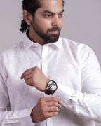 Man wearing a white shirt and gray pants against a plain background